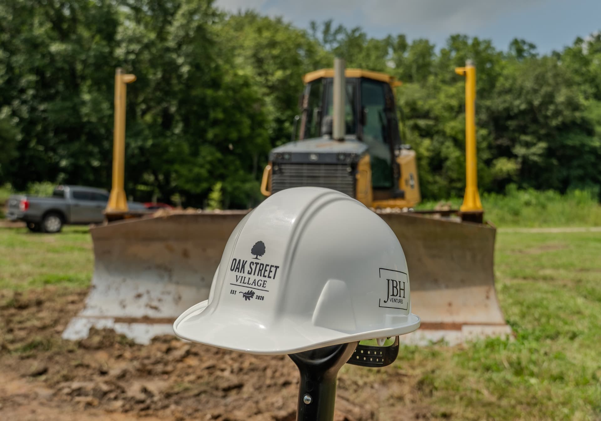 Oak Street Village hard hat at the groundbreaking site, with construction equipment behind